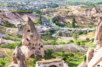 Travel to Turkey - rock-cut house and view of bus stop in Uchisar town in Cappadocia in spring