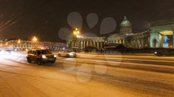 view of Kazansky Cathedral on snow-covered Nevsky Prospect street in night snowfall in Saint Petersburg city in March