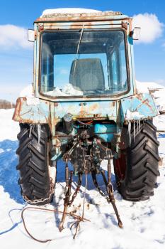 broken tractor on snowy road in russian village Kikino in Smolensk Oblast of Russia in sunny winter day