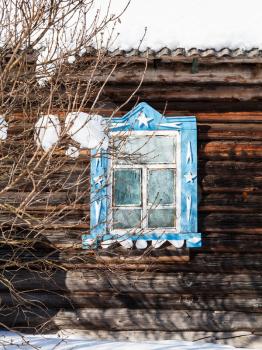 carved window in wooden wall of old typical russian rural house in winter in little village in Smolensk region of Russia
