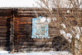 wooden wall with carved window of old typical russian rural house in winter in little village in Smolensk region of Russia