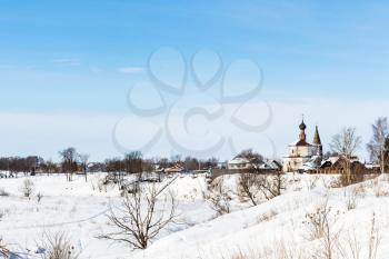 view of Suzdal town with Holy Cross Exaltation and St Cosmas and St Damian Churches in Korovniki district on riverbank of frozen river in winter in Vladimir oblast of Russia
