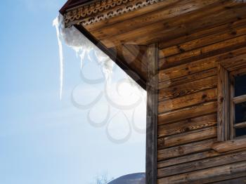 icicle illuminated by sun on roof of old log house in Suzdal town in spring in Vladimir oblast of Russia