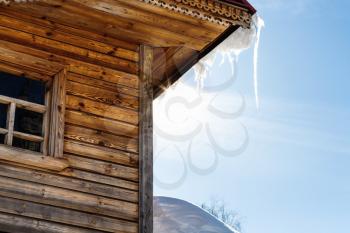 icicle illuminated by sun on roof of wooden house in Suzdal town in spring in Vladimir oblast of Russia