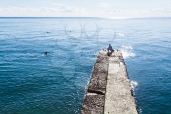 travel to Crimea - fisherman on pier of embankment on coast of Black Sea in Alushta city in morning