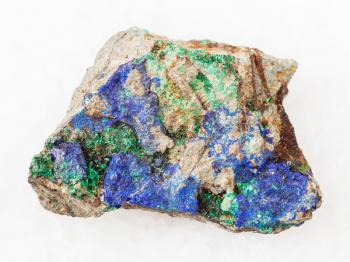 macro shooting of natural mineral rock specimen - blue Azurite and green Malachite on rough stone on white marble background from Ural Mountains, Russia