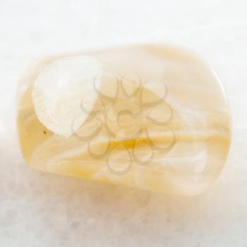 macro shooting of natural mineral rock specimen - polished yellow banded Agate gemstone on white marble background