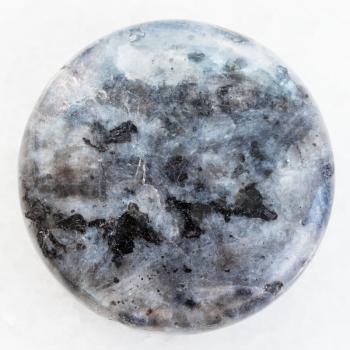 macro shooting of natural mineral rock specimen - bead from gray Labradorite gemstone on white marble background