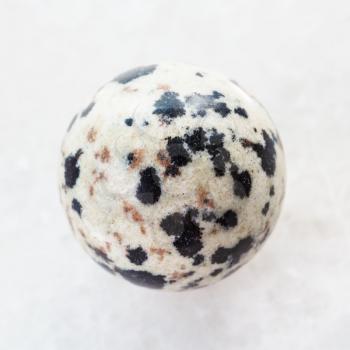 macro shooting of natural mineral rock specimen - ball from Dalmatian Jasper gemstone on white marble background
