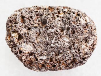macro shooting of natural mineral rock specimen - brown pumice stone on white marble background from Sicily
