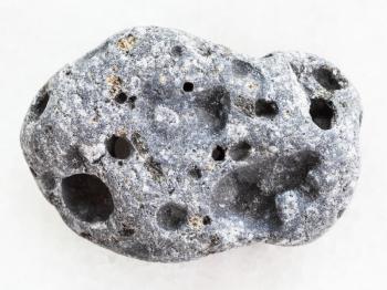 macro shooting of natural mineral rock specimen - gray pumice stone on white marble background from Sicily