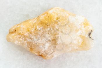 macro shooting of natural mineral rock specimen - pebble of yellow Calcite stone on white marble background