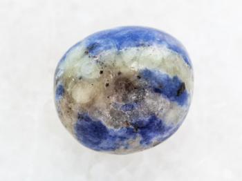 macro shooting of natural mineral rock specimen - polished Sodalite gem stone on white marble background
