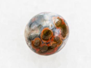 macro shooting of natural mineral rock specimen - polished orbicular jasper gemstone on white marble background