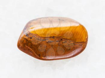 macro shooting of natural mineral rock specimen - polished tiger's eye gemstone on white marble background from South Africa
