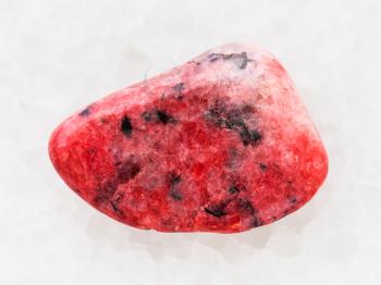 macro shooting of natural mineral rock specimen - polished red Agate gemstone on white marble background from Mexico