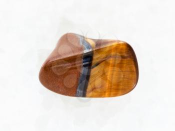 macro shooting of natural mineral rock specimen - polished tiger eye gemstone on white marble background from South Africa