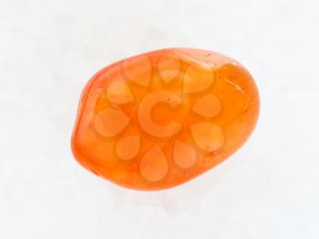macro shooting of natural mineral rock specimen - tumbled Carnelian gemstone on white marble background