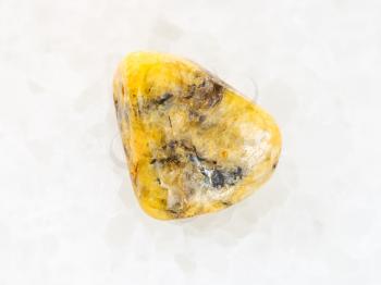 macro shooting of natural mineral rock specimen - tumbled yellow Agate gemstone on white marble background from Mexico