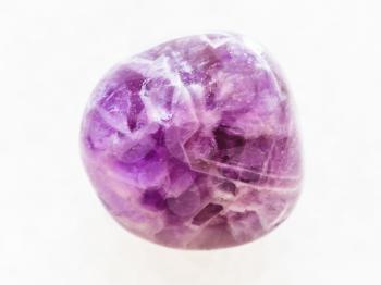 macro shooting of natural mineral rock specimen - tumbled Amethyst gem on white marble background