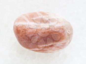 macro shooting of natural mineral rock specimen - tumbled moonstone gemstone on white marble background