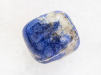 macro shooting of natural mineral rock specimen - tumbled Sodalite gemstone on white marble background