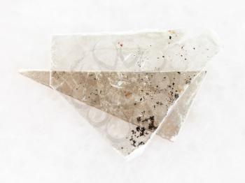 macro shooting of natural mineral rock specimen - rough muscovite mica lamina on white marble background