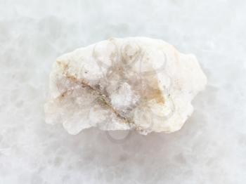 macro shooting of natural mineral rock specimen - scheelite vein (tungsten ore) in rough stone on white marble background