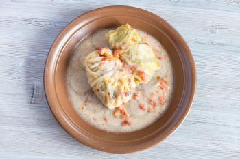 russian cuisine - top view of stewed cabbage rolls on ceramic plate on gray wooden board