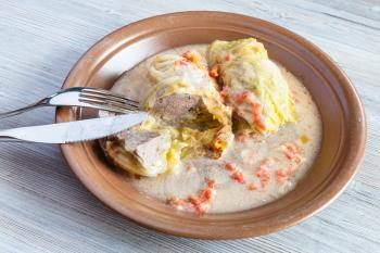 russian cuisine - stewed cabbage rolls stuffed with minced meat with rice on ceramic plate on gray wooden table