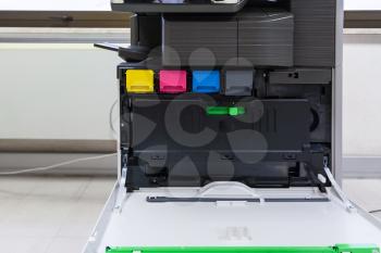 copier with four toner cartridges with open cover in office hall
