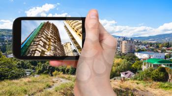 travel concept - tourist photographs new houses in Alushta town in Crimea on smartphone