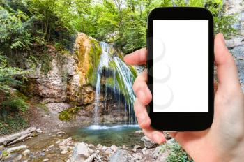 travel concept - tourist photographs Ulu-Uzen river with Djur-djur waterfall in Haphal Gorge of Habhal Hydrological Reserve natural park in Crimea on smartphone with cut out screen for advertising