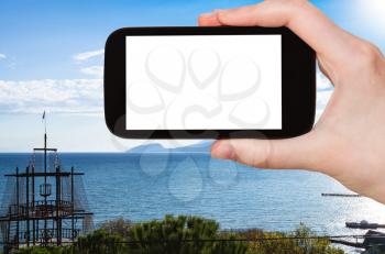 travel concept - tourist photographs Crimean Southern Coast of Black sea near Malorechenskoe (Malorichenske) village in Crimea in september on smartphone with cut out screen for advertising logo