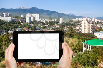 travel concept - tourist photographs Alushta city skyline from Castle Hill in Crimea in september morning on tablet with cut out screen for advertising logo