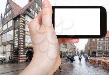 travel concept - tourist photographs Bremer Marktplatz (Bremen Market Square) in Germany in autumn rain on smartphone with cut out screen for advertising logo