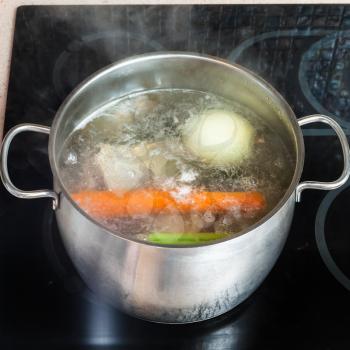cooking soup - boiling meat broth in stockpot on ceramic cooker