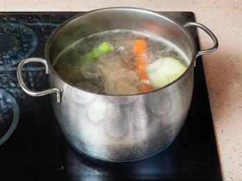 cooking soup - simmering meat stock in stockpot on ceramic cooker