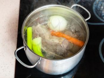 cooking soup - simmering beef broth in stockpot on ceramic cooker