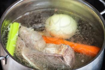 cooking soup - boiling beef broth in steel stewpan close up