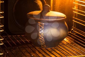 cooking soup - closed ceramic pot with stewed cabbage in illuminated electric oven
