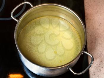 cooking soup - clear fat beef bouillon in steel stockpot on ceramic cooker