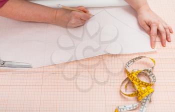 tailor traces the hand drawn clothing pattern on tracing paper