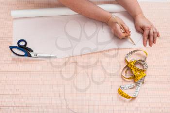 tailor copies the hand drawn clothing pattern on tracing paper