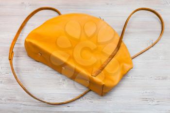 back side of handmade yellow leather bag on wooden table