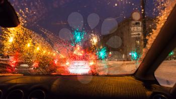 poor visibility through wet windscreen while driving car on street in Moscow city in winter evening in snowfall