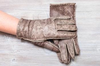 workshop on sewing gloves - top view of female hand in new hand-made glove on wooden background