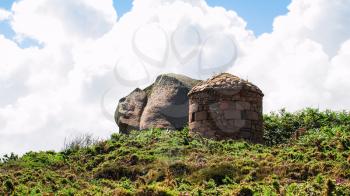 travel to France - boulder and old stone building in Ploumanac'h site of Perros-Guirec commune on Pink Granite Coast of Cotes-d'Armor department of Brittany in sunny summer day