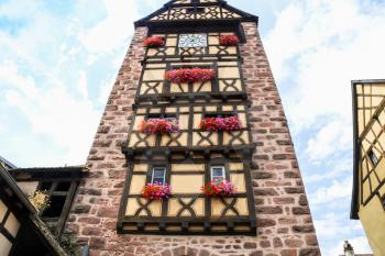 travel to France - facade of old clock tower Riquewihr town in Alsace Wine Route