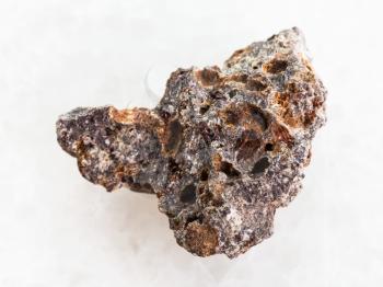 macro shooting of natural mineral rock specimen - rough Basalt stone on white marble background